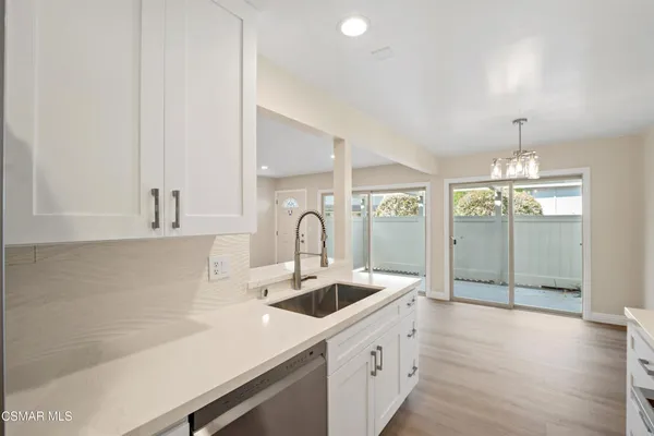 a large kitchen with stainless steel appliances a large counter top a sink a refrigerator and a stove