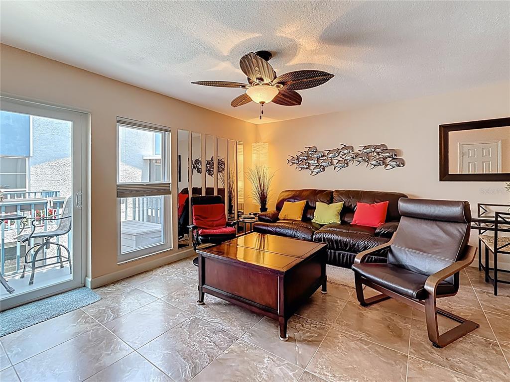 230 Medallion Boulevard, Unit G Madeira Beach, FL 33708 - Photo 13 of 38 a living room with furniture a window and a chandelier