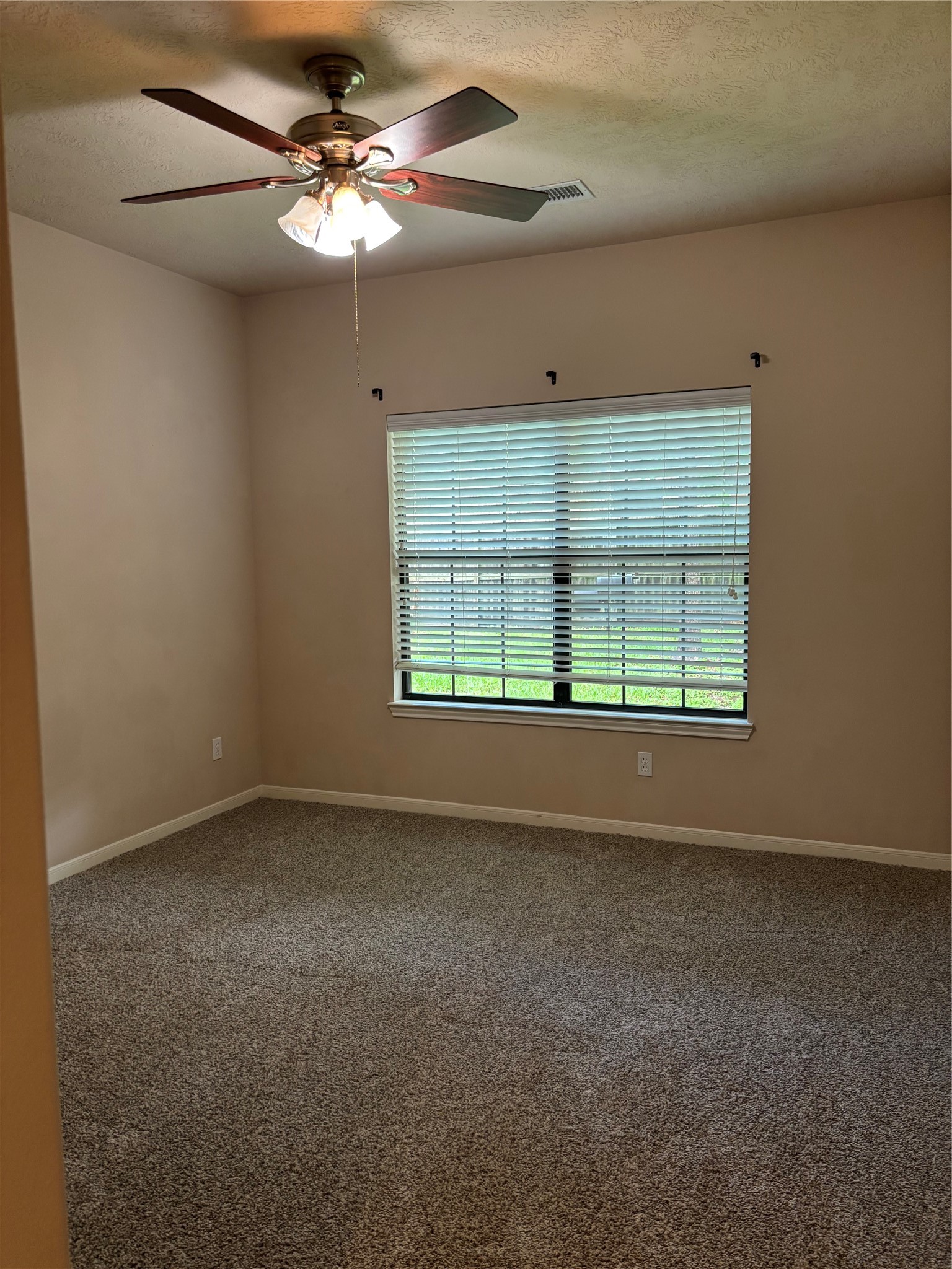 3238 Glenforest Road Montgomery, TX 77356 - Photo 31 of 41 A cozy, carpeted room with neutral walls, a ceiling fan, and a large window with blinds, offering natural light and a view of the outdoors.