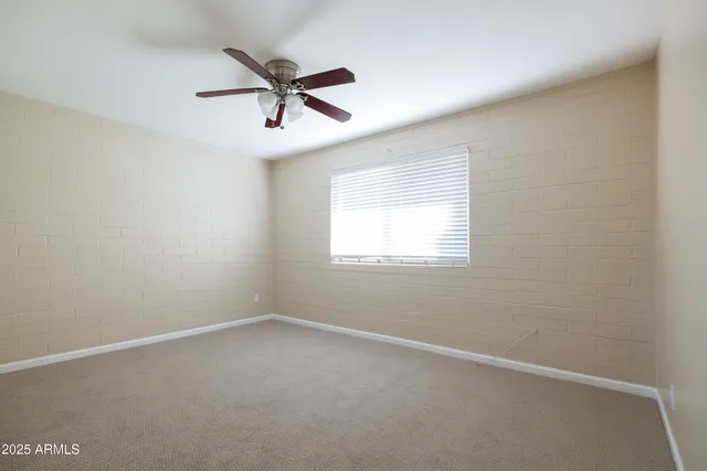 an empty room with a window and a fan