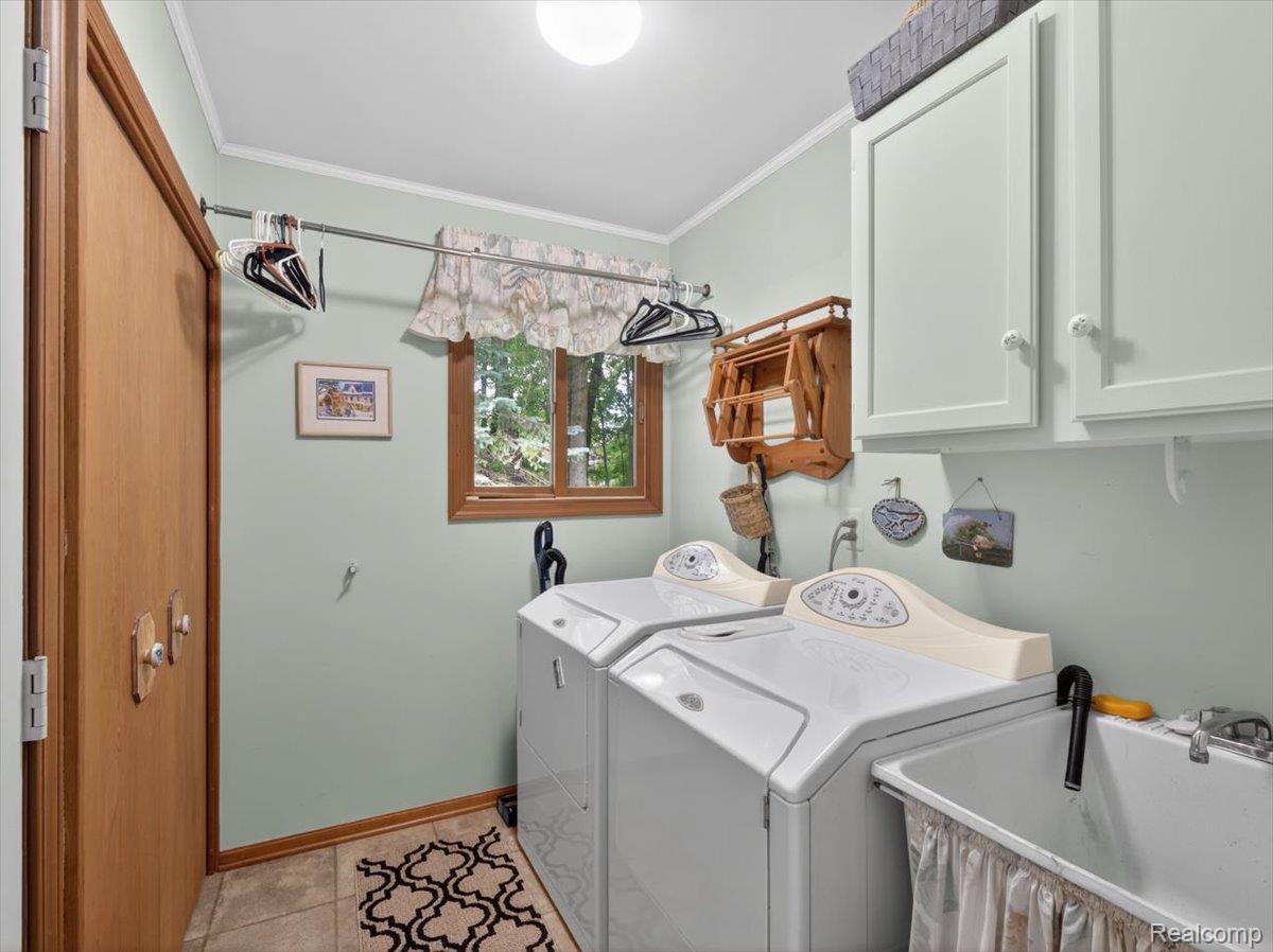 9714 Naiad Road Clarkston, MI 48348 - Photo 25 of 61 Dedicated utility area with ceramic tile flooring, including a well-organized laundry room equipped with a sink, drying rack, cupboards, and a convenient storage closet.