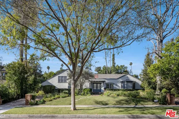 a front view of a house with garden and trees