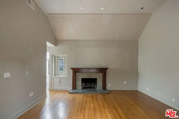 a view of an empty room with wooden floor and a fireplace