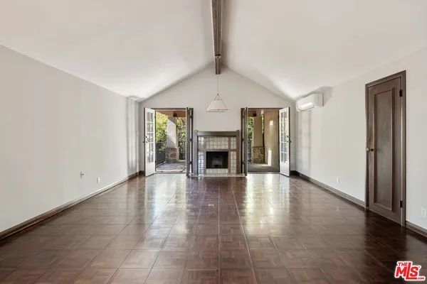 an empty room with wooden floor fireplace and windows