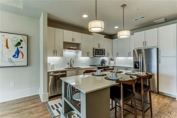 a kitchen with a refrigerator a stove a sink dishwasher a dining table and chairs with wooden floor