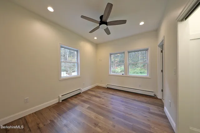 an empty room with wooden floor and windows