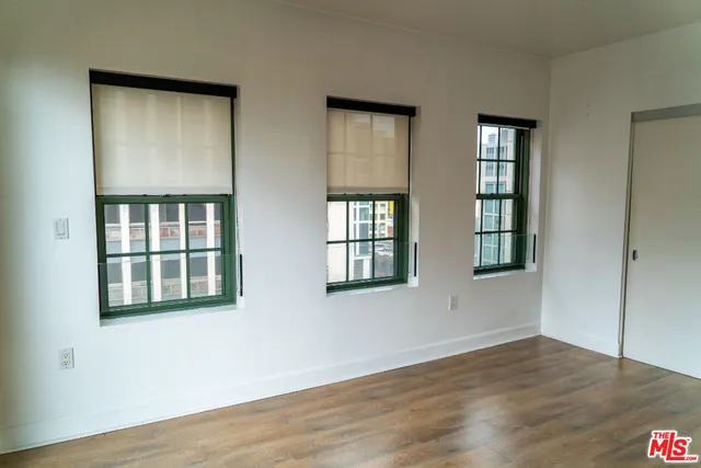 a view of an empty room with wooden floor and windows