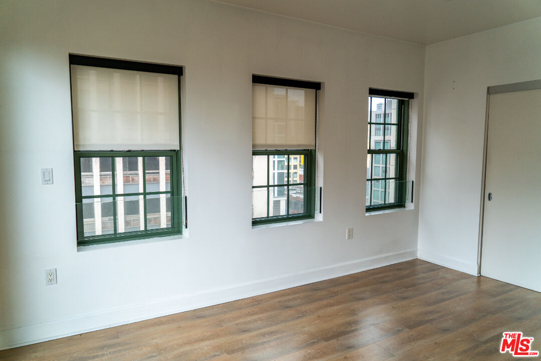 416 South Spring Street, Unit 906 Los Angeles, CA 90013 - Photo 12 of 18 a view of an empty room with wooden floor and windows