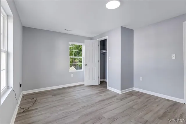 an empty room with wooden floor and windows