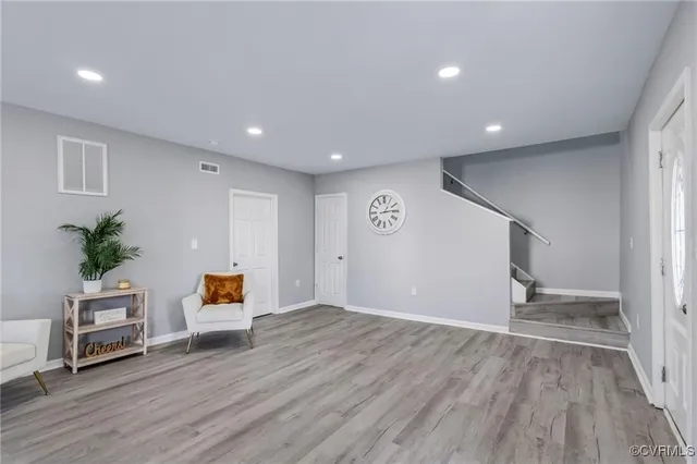 a view of an empty room with wooden floor and a potted plant