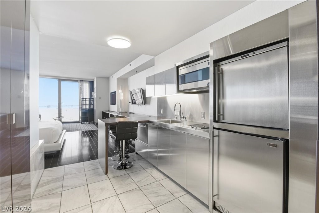 4381 West Flamingo Road, Unit 10306 Las Vegas, NV 89103 - Photo 2 of 26 This modern kitchen features sleek stainless steel appliances and an open-concept design with direct outdoor views.