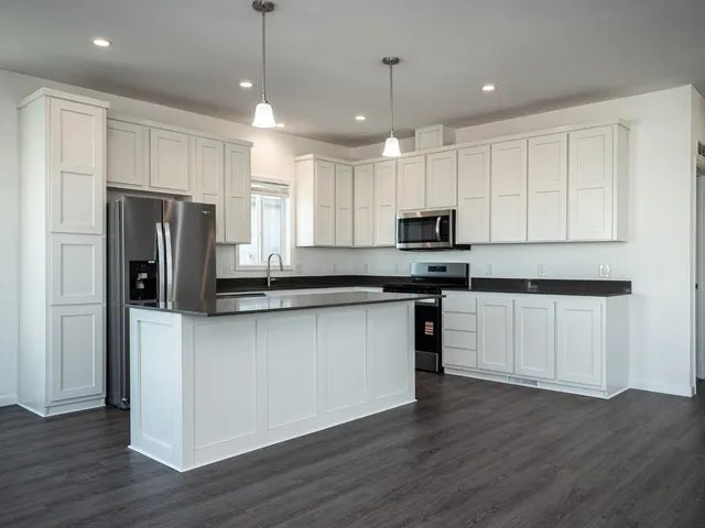 a kitchen with stainless steel appliances granite countertop white cabinets and a stove top oven