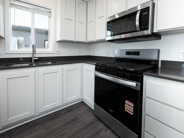 an open kitchen with white cabinets wooden floor and stainless steel appliances
