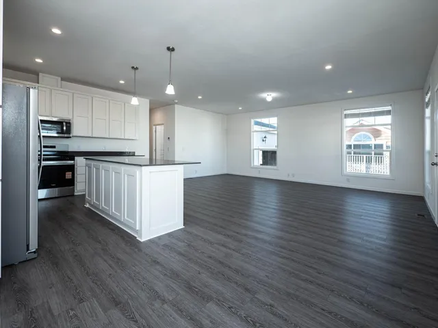 a kitchen with stainless steel appliances granite countertop a sink a wooden floor and a large window