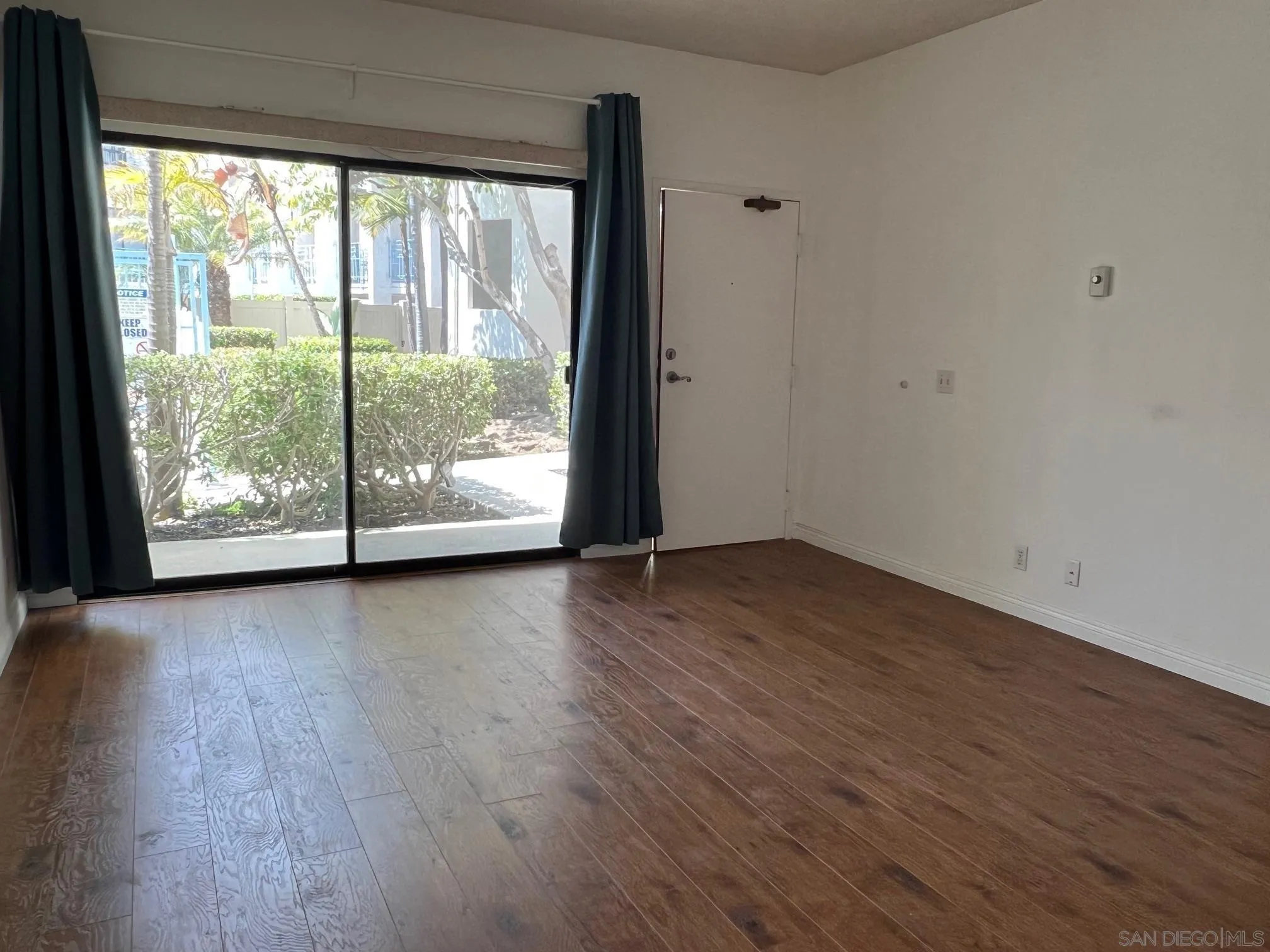 8310 Regents Road, Unit 1E San Diego, CA 92122 - Photo 7 of 23 an empty room with wooden floor and windows