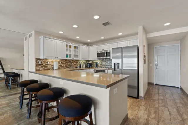 a kitchen with stainless steel appliances granite countertop a table chairs sink and cabinets