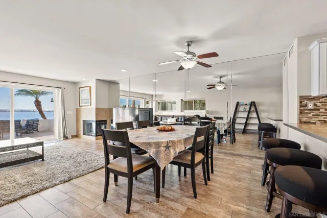 a view of a dining room and livingroom with furniture wooden floor a rug a flat screen tv a rug and a chandelier