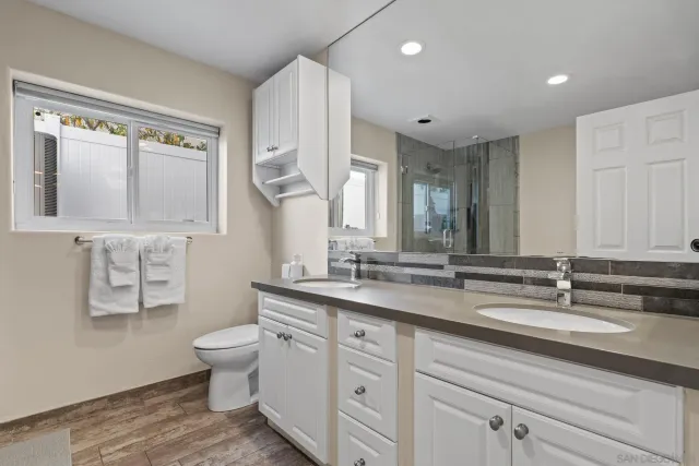a bathroom with double vanity sinks a mirror and a shower