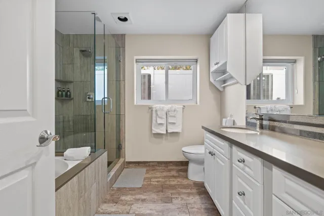 a spacious bathroom with a granite countertop sink a toilet a mirror and shower