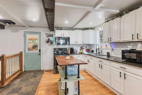 a kitchen with stainless steel appliances granite countertop a stove top oven a sink dishwasher and a refrigerator with wooden floor