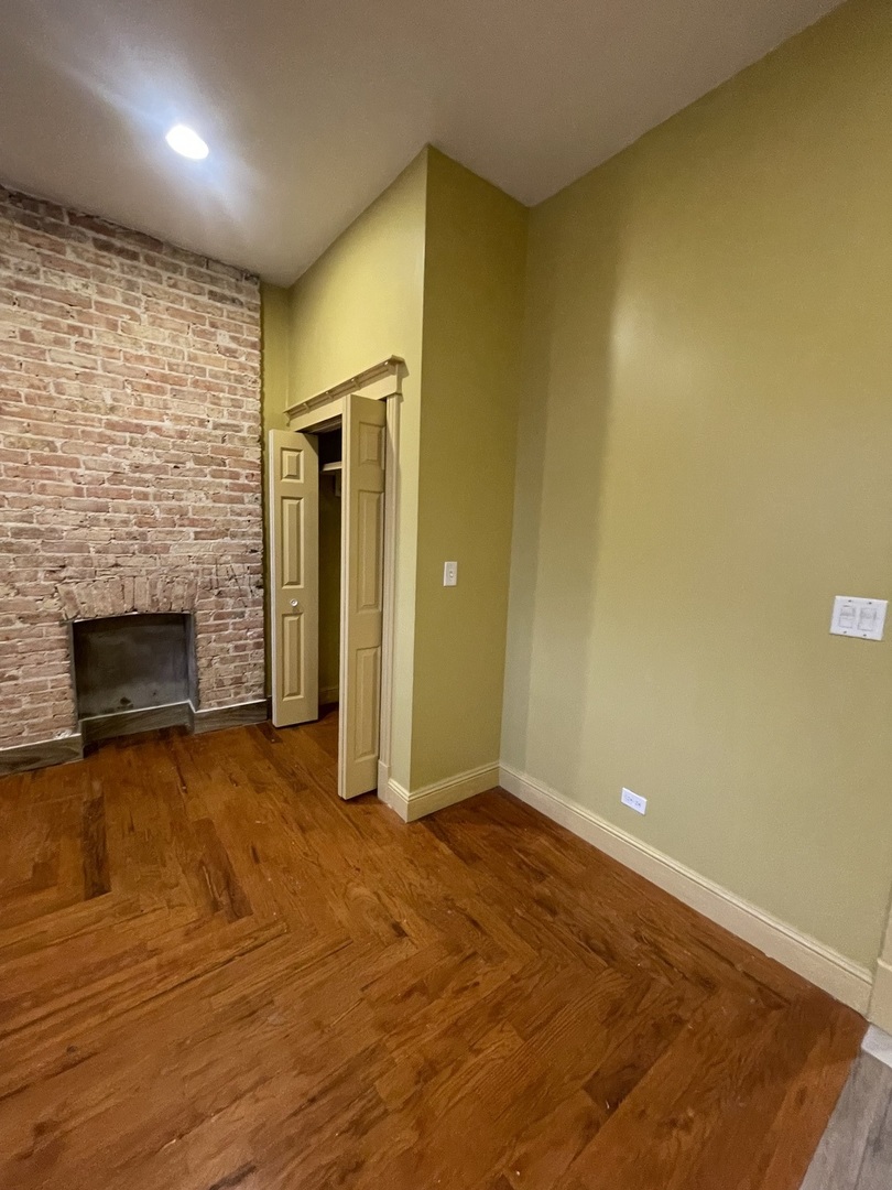 3341 West Walnut Street, Unit 1 Chicago, IL 60624 - Photo 8 of 10 an empty room with wooden floor and a fireplace