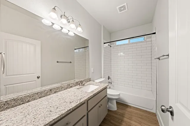 a bathroom with a granite countertop sink a toilet and shower