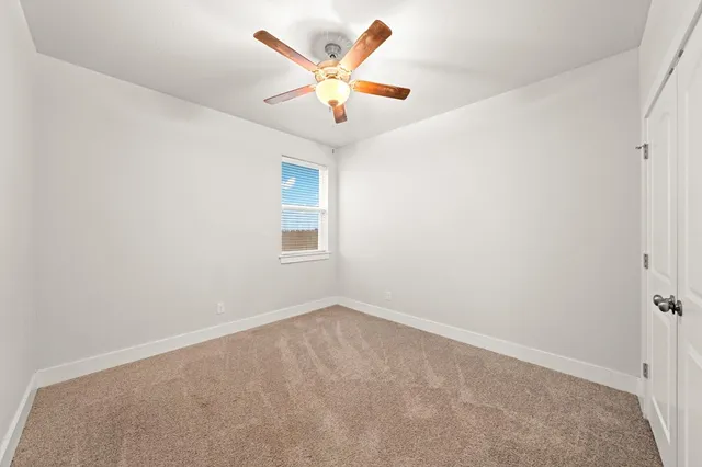 an empty room with window and ceiling fan