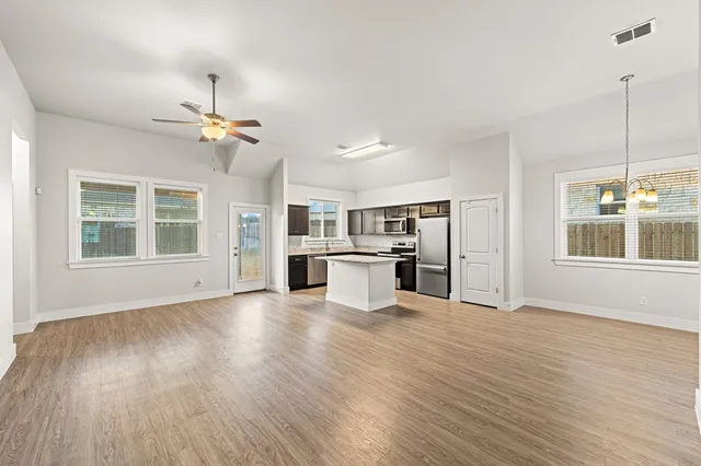 a view of an empty room with window and wooden floor