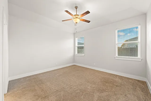 an empty room with ceiling fan and window