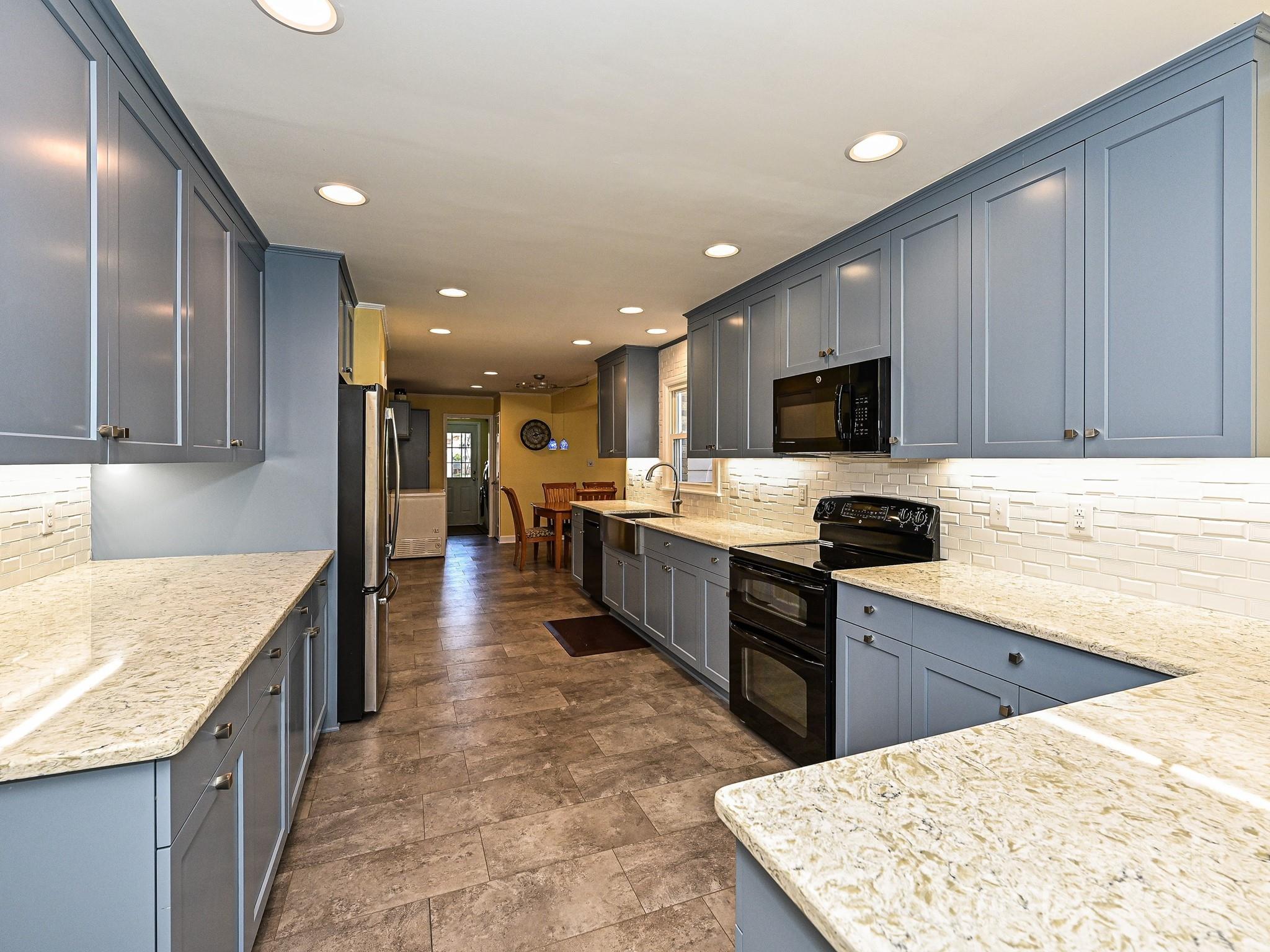 a large kitchen with kitchen island granite countertop a sink counter space and stainless steel appliances