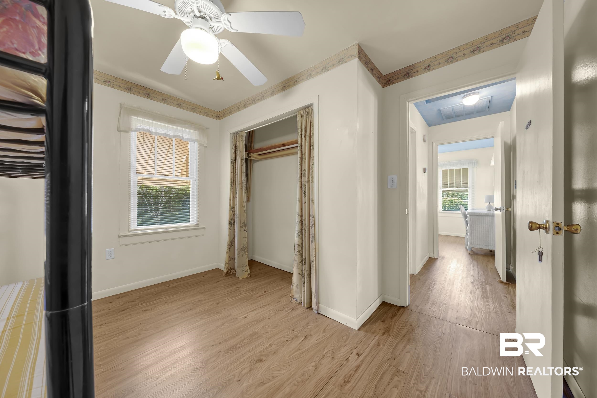 304 West Myrtle Avenue Foley, AL 36535 - Photo 16 of 29 Bedroom with wood-finish flooring, a ceiling fan with integrated lighting, a single window with white trim, and a closet with patterned drapes