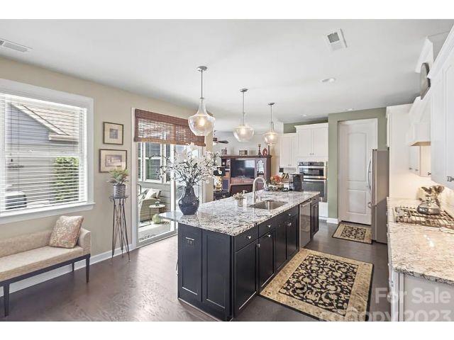 1292 Independence Street Fort Mill, SC 29708 - Photo 10 of 39 a kitchen with stainless steel appliances kitchen island granite countertop a stove a sink dishwasher and white cabinets with wooden floor