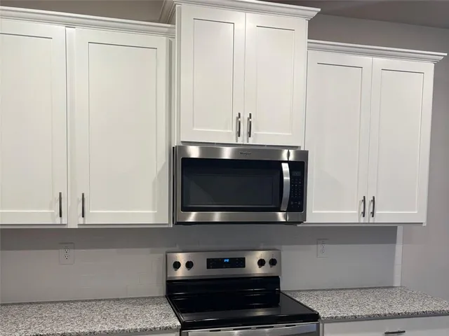 a kitchen with stainless steel appliances granite countertop white cabinets and a stove