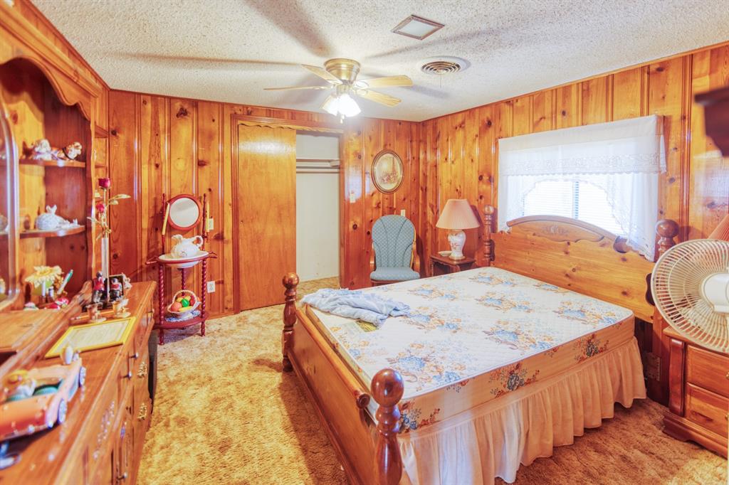 700 South Washington Street Pilot Point, TX 76258 - Photo 7 of 14 a bedroom with a bed and dresser with mirror