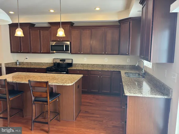 a kitchen with granite countertop wooden floors cabinets a dining table and chairs