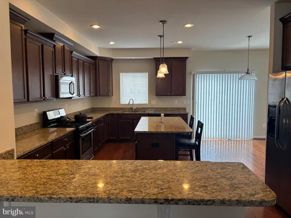 a kitchen with stainless steel appliances granite countertop wooden cabinets a stove a sink and a microwave