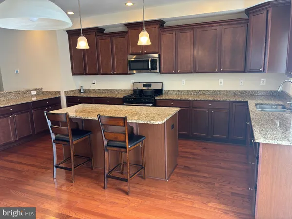 a kitchen with stainless steel appliances granite countertop wooden cabinets a sink and dishwasher a stove with wooden floor