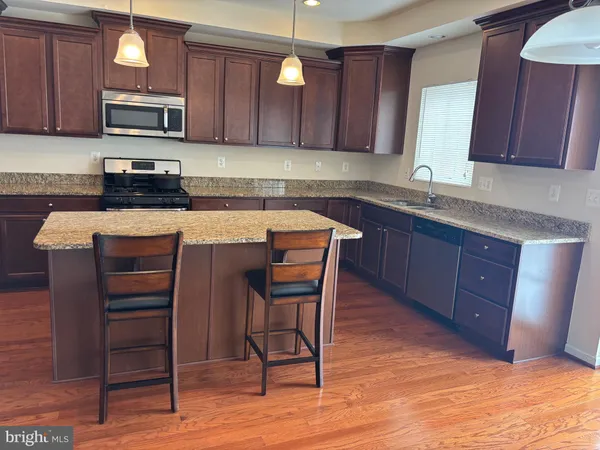 a kitchen with stainless steel appliances granite countertop a table chairs sink and cabinets