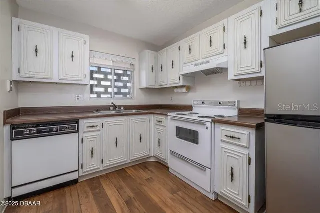 a kitchen with granite countertop white cabinets and white appliances