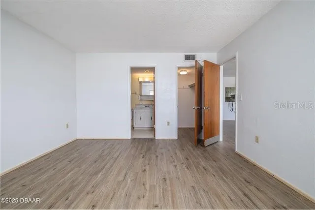 a view of an empty room with wooden floor and closet