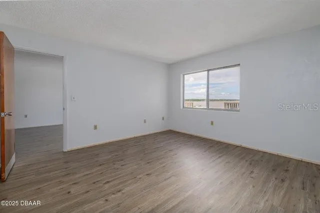 an empty room with wooden floor and window