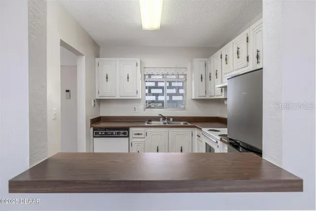 a kitchen with stainless steel appliances granite countertop a stove a refrigerator a sink a stove and white cabinets