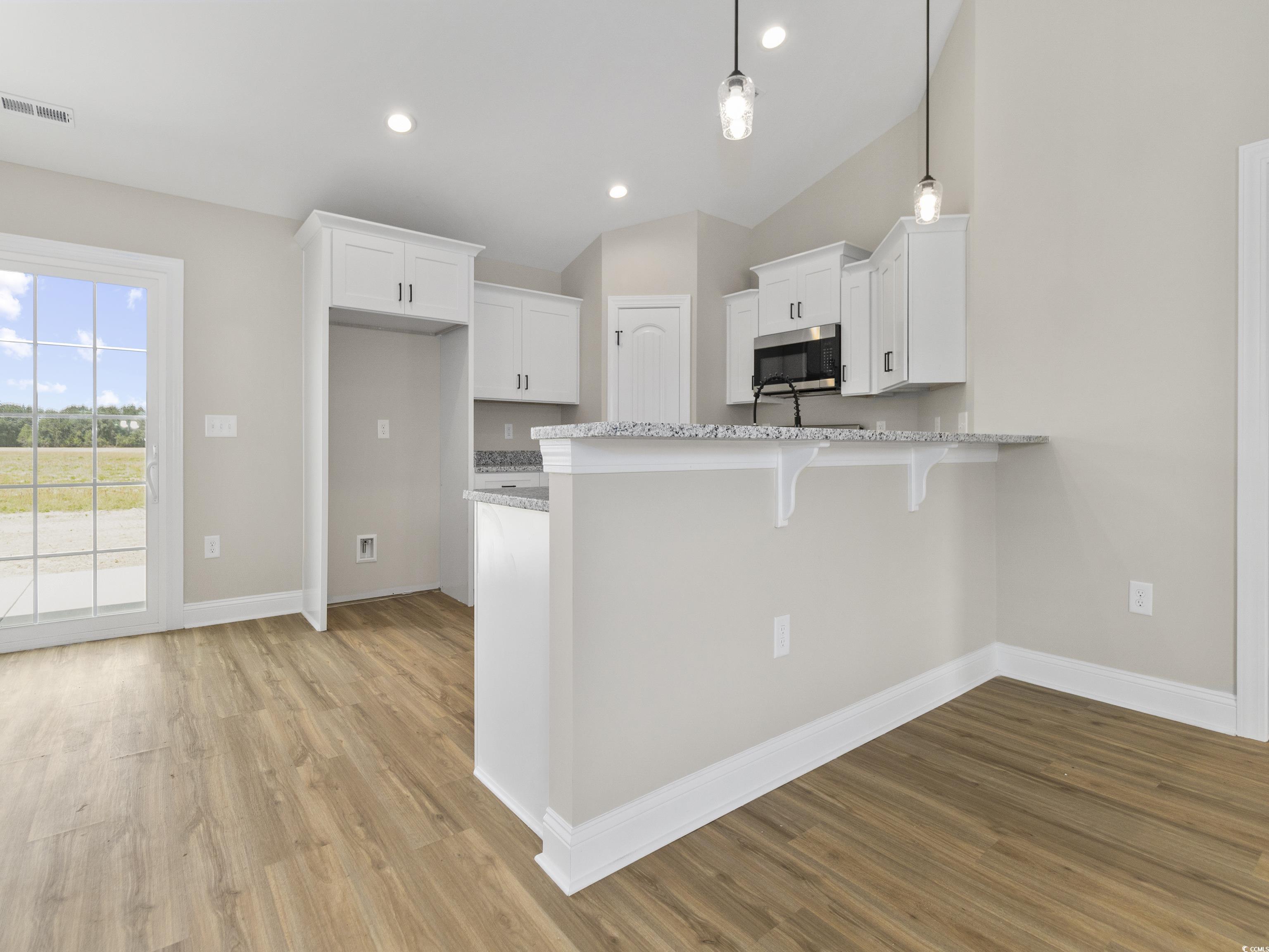 837 Highway 67 Loris Sc 29569 Loris, SC 29569 - Photo 15 of 31 Kitchen featuring stainless steel microwave, a peninsula, light wood-style flooring, white cabinetry, and visible vents