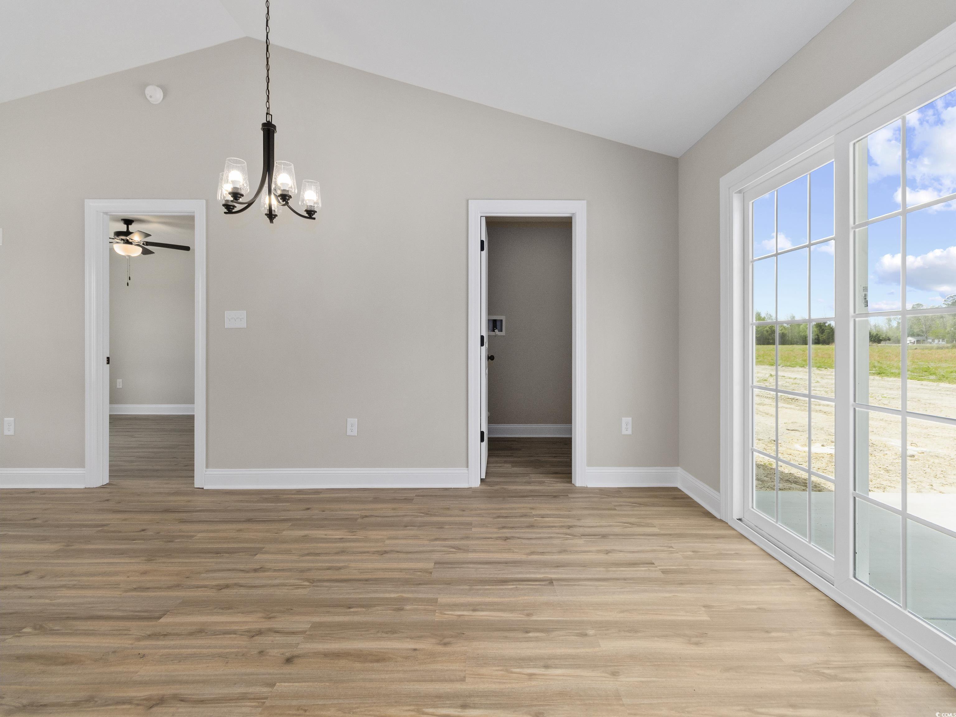 837 Highway 67 Loris Sc 29569 Loris, SC 29569 - Photo 16 of 31 Unfurnished dining area with baseboards, light wood finished floors, vaulted ceiling, and ceiling fan with notable chandelier