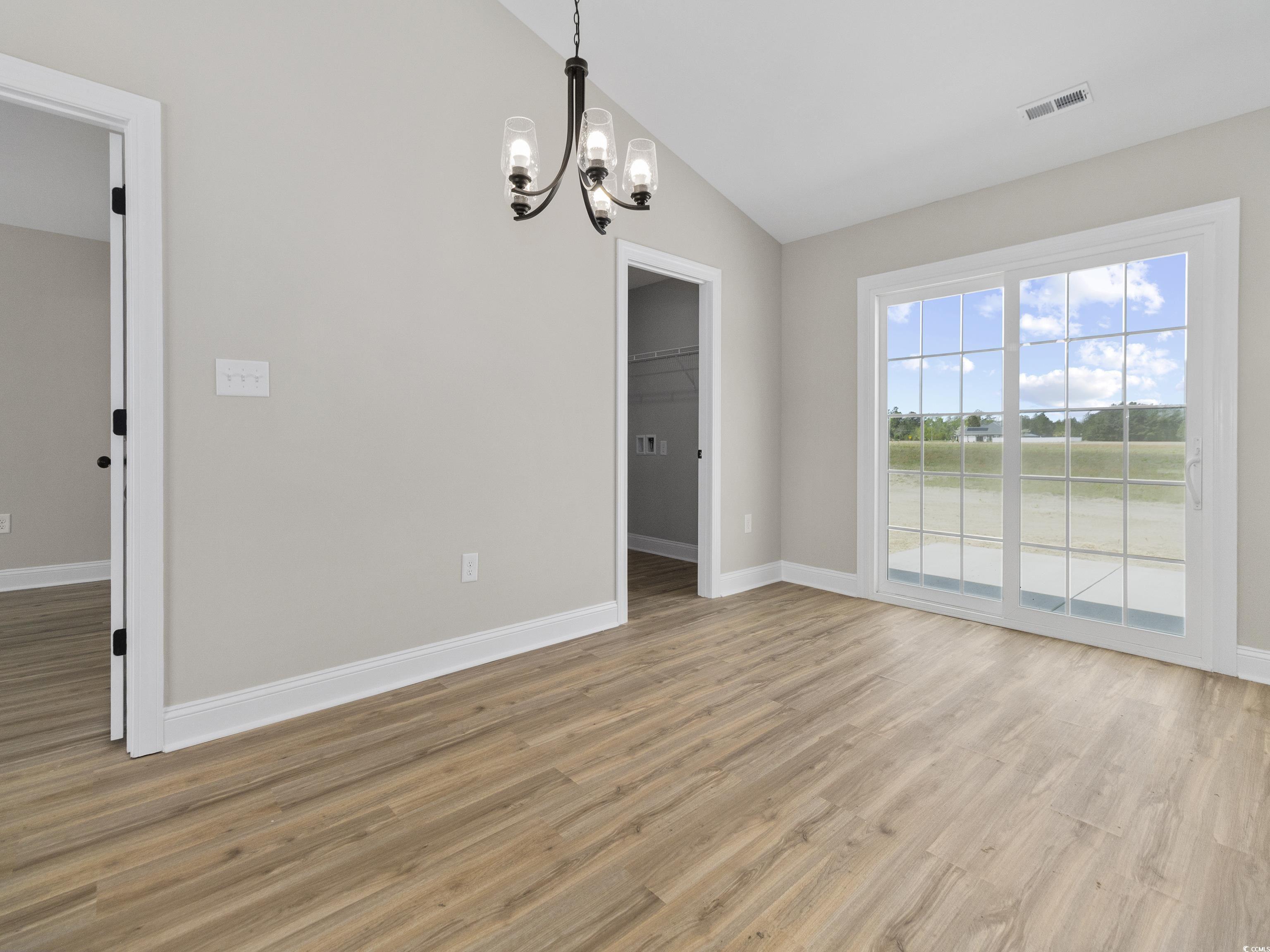 837 Highway 67 Loris Sc 29569 Loris, SC 29569 - Photo 18 of 31 Empty room featuring light wood-type flooring, visible vents, lofted ceiling, baseboards, and a notable chandelier