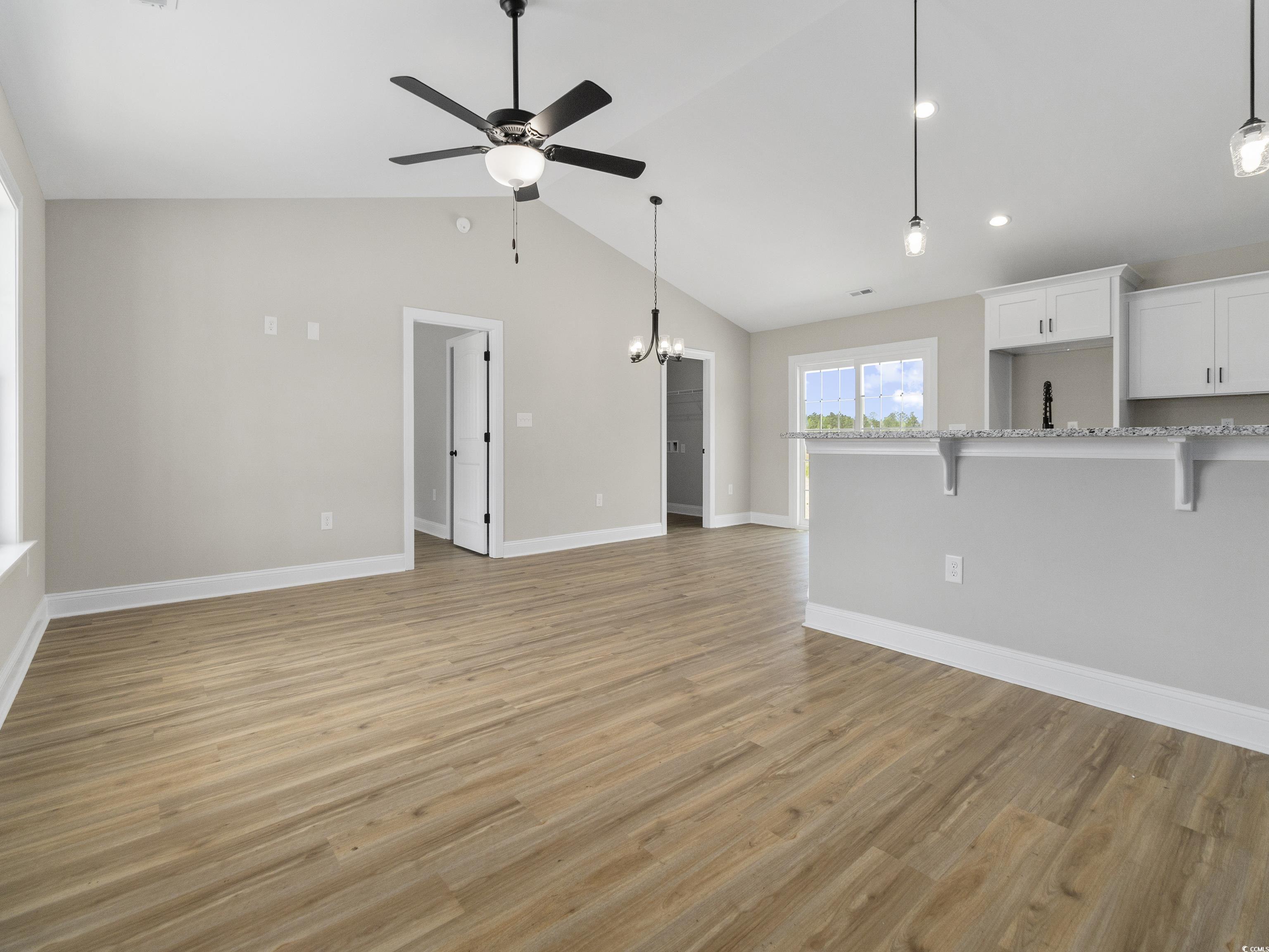 837 Highway 67 Loris Sc 29569 Loris, SC 29569 - Photo 8 of 31 Unfurnished living room featuring light wood-type flooring, ceiling fan with notable chandelier, baseboards, and lofted ceiling
