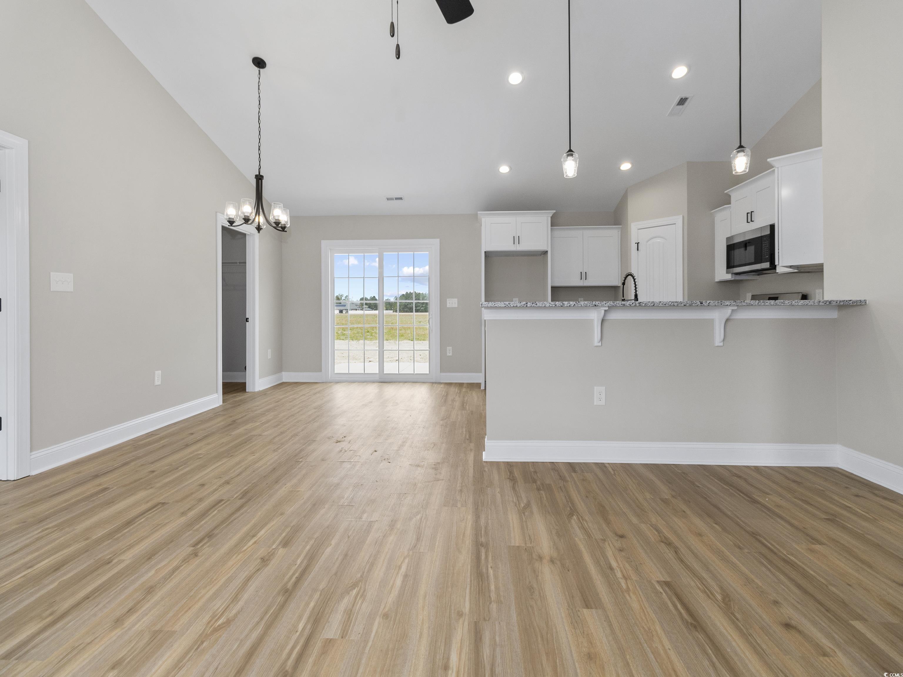 837 Highway 67 Loris Sc 29569 Loris, SC 29569 - Photo 9 of 31 Kitchen featuring stainless steel microwave, a breakfast bar, white cabinetry, light wood finished floors, and ceiling fan with notable chandelier