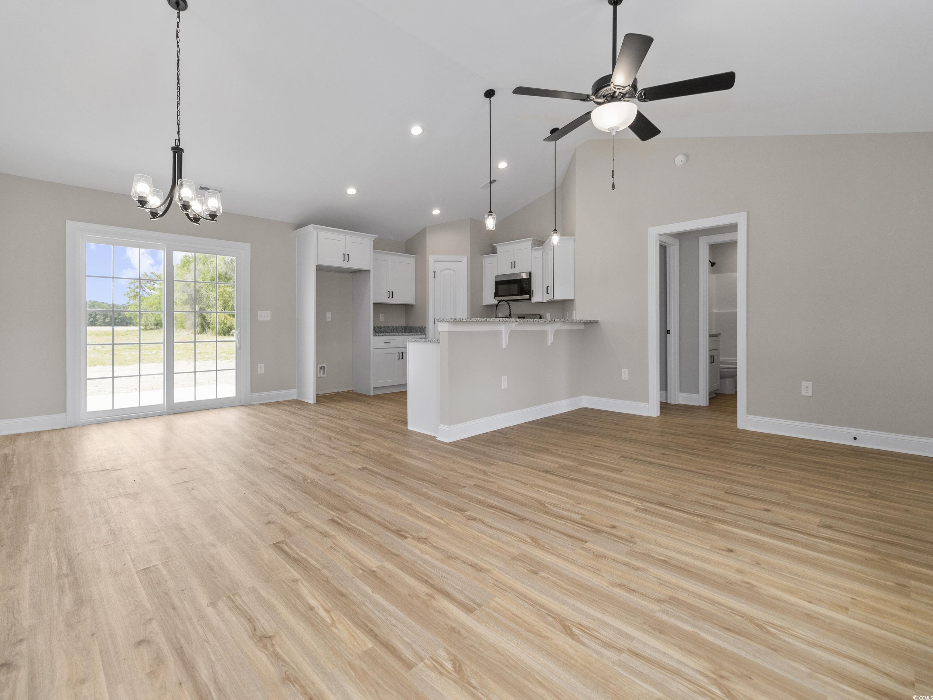 837 Highway 67 Loris Sc 29569 Loris, SC 29569 - Photo 10 of 31 Unfurnished living room with light wood-style flooring, ceiling fan with notable chandelier, and baseboards