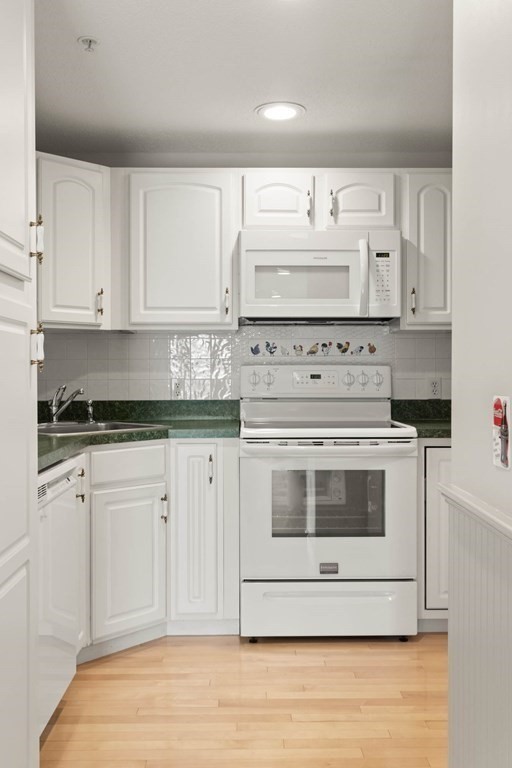 2 Ocean Avenue, Unit 3D Gloucester, MA 01930 - Photo 13 of 30 a white kitchen with granite countertop white cabinets and white appliances