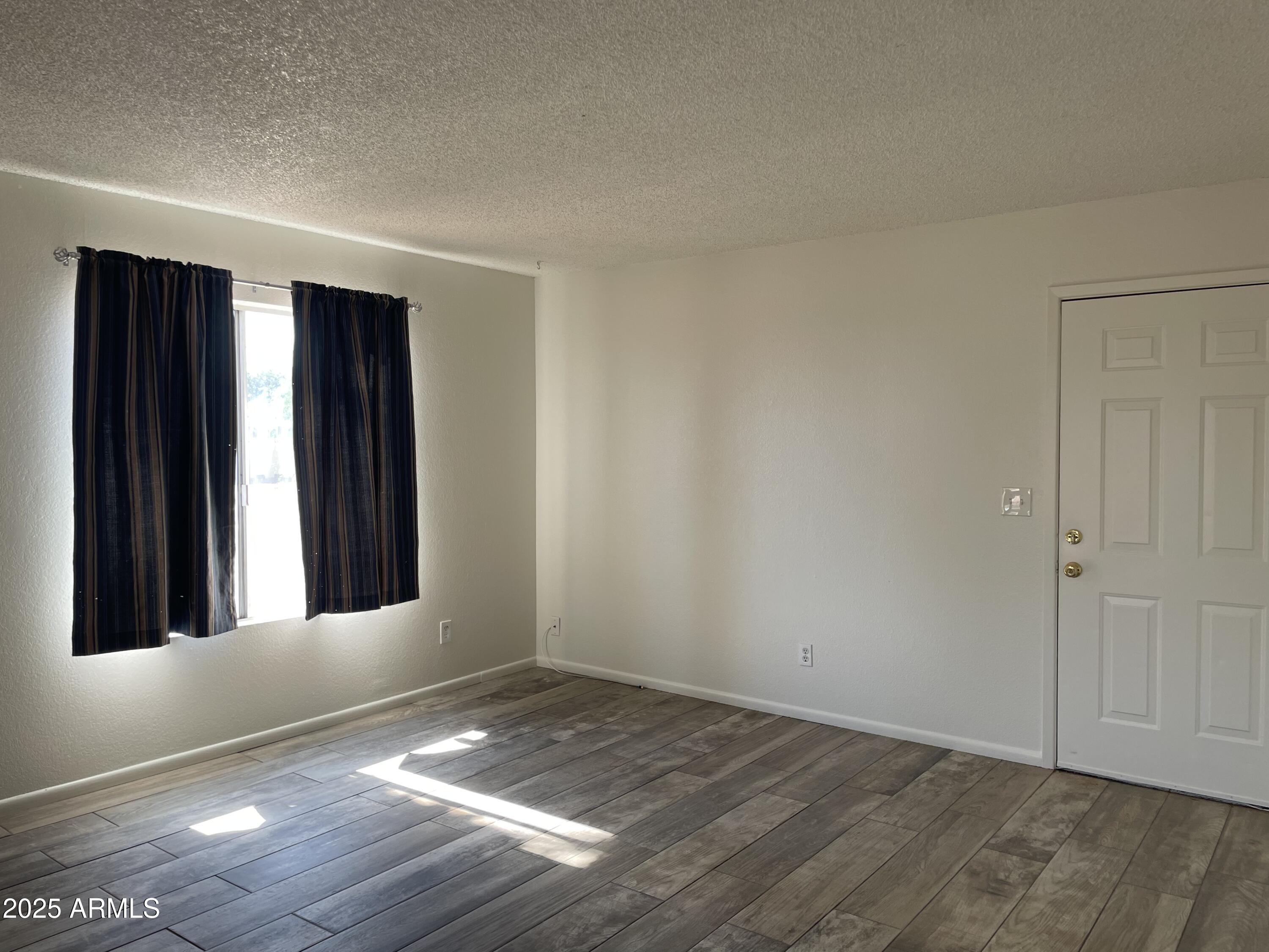 143 South Mountain Road, Unit 1 Apache Junction, AZ 85120 - Photo 9 of 17 an empty room with wooden floor and windows